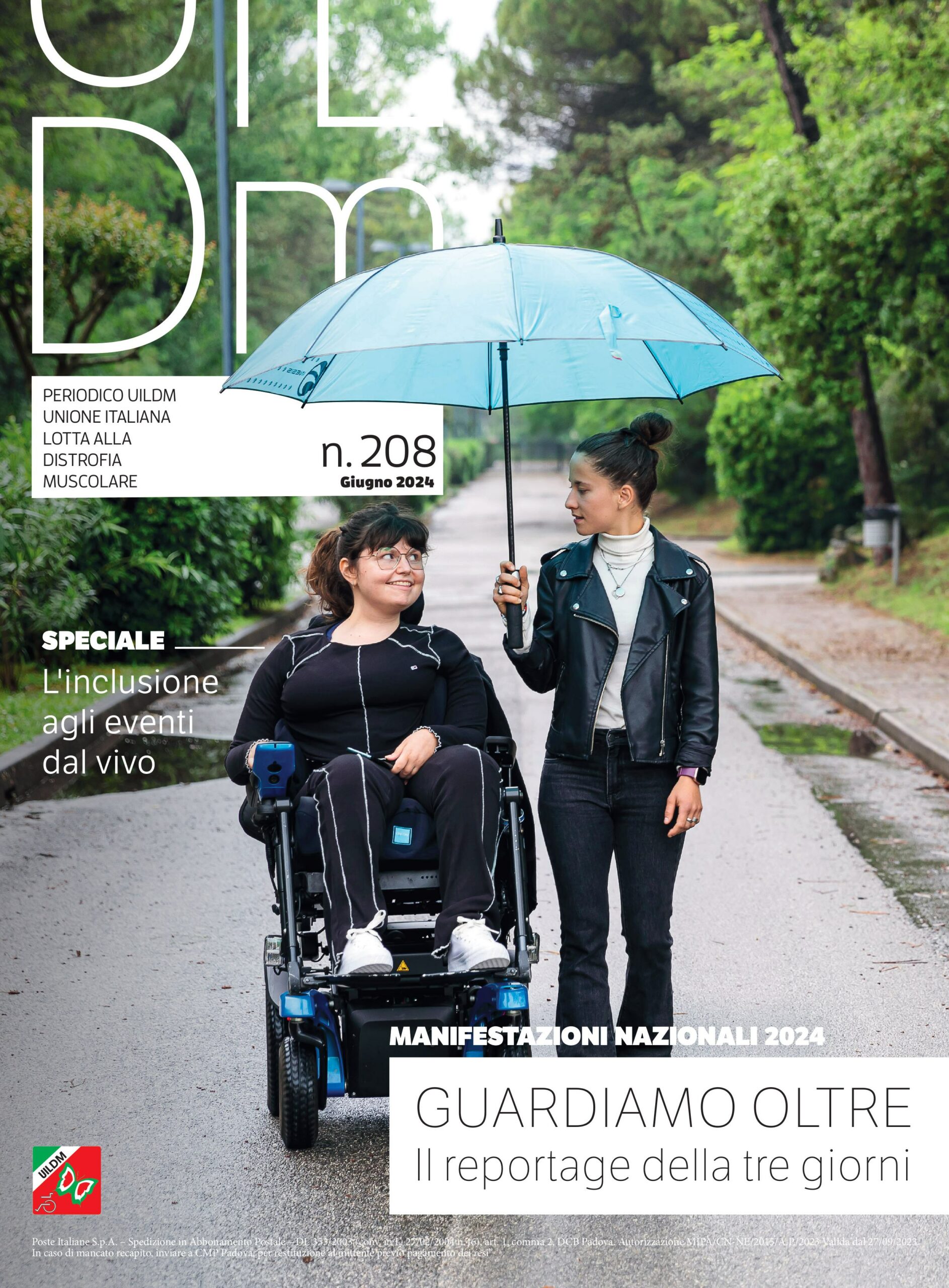 persona che regge un ombrello azzurro in un viale alberato e accompagna una persona in carrozzina